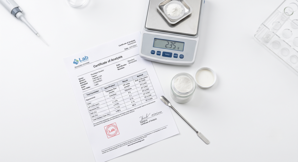 Certificate of analysis document for resistant dextrin showing fiber content moisture and pH values beside soluble tapioca fiber powder jar and lab scale